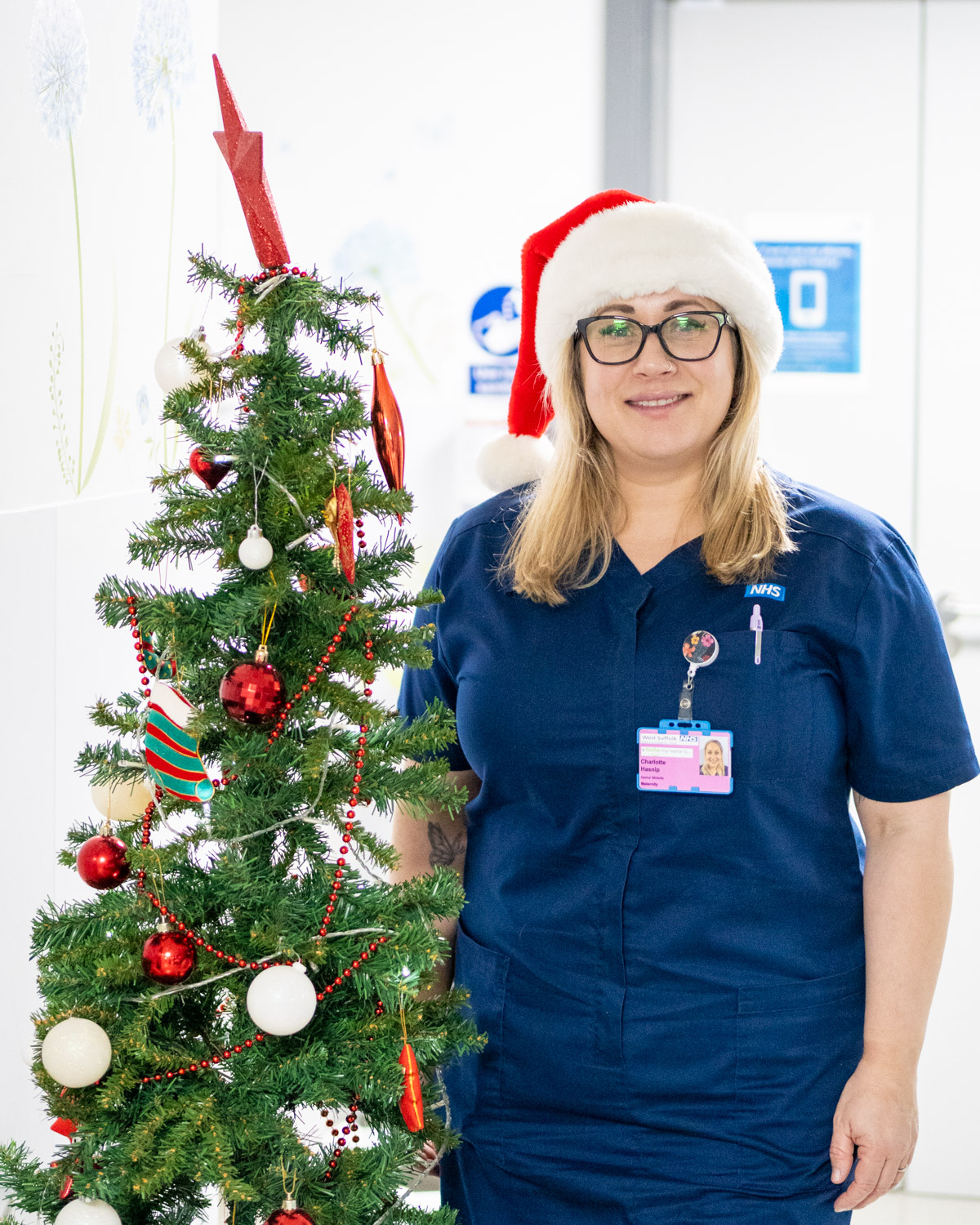 Nurse stood next to a Christmas tree