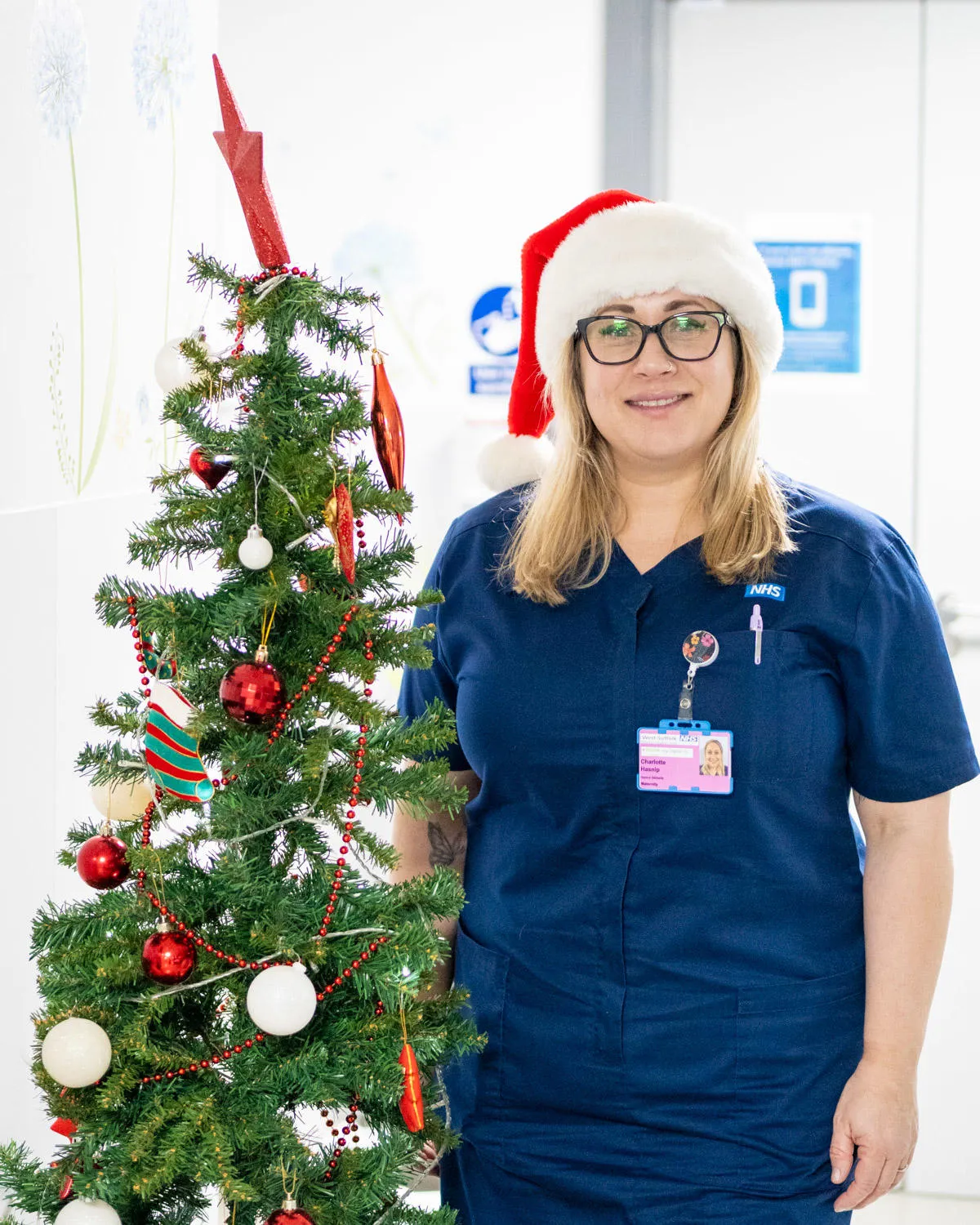 Nurse stood next to a Christmas tree