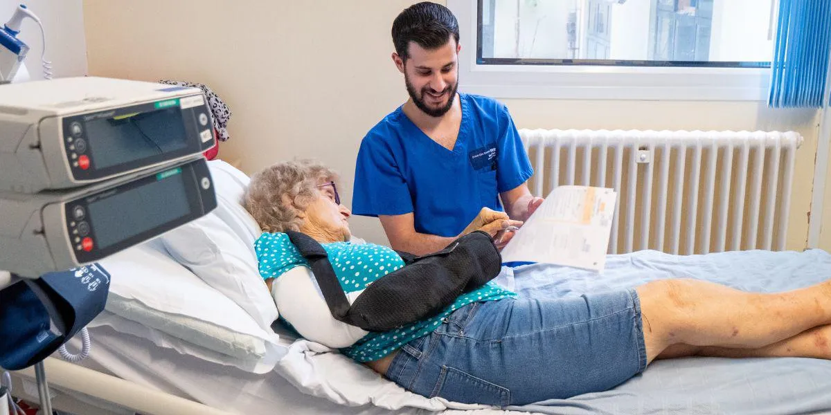 Nurse with a patient in a bed on a hospital ward