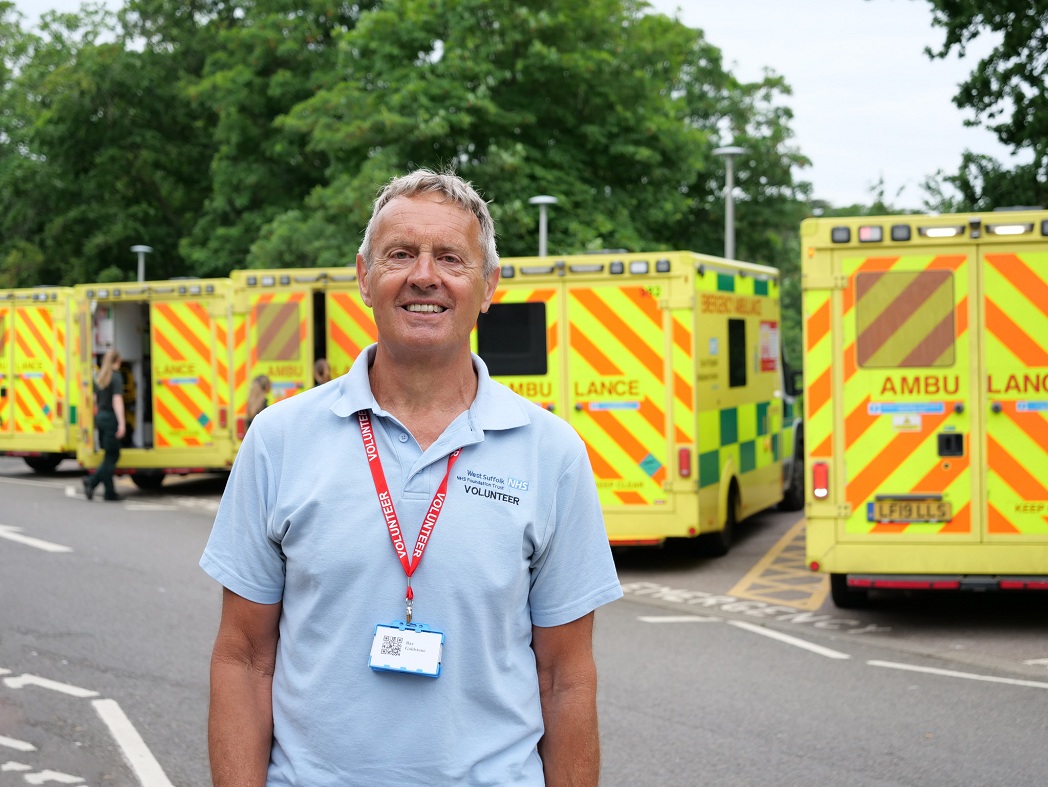 Volunteer standing in front of a row of ambulances