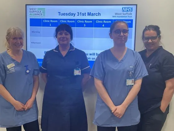 Four team members from WSFT community nursing team, they are standing together and smiling, and are wearing blue scrubs.