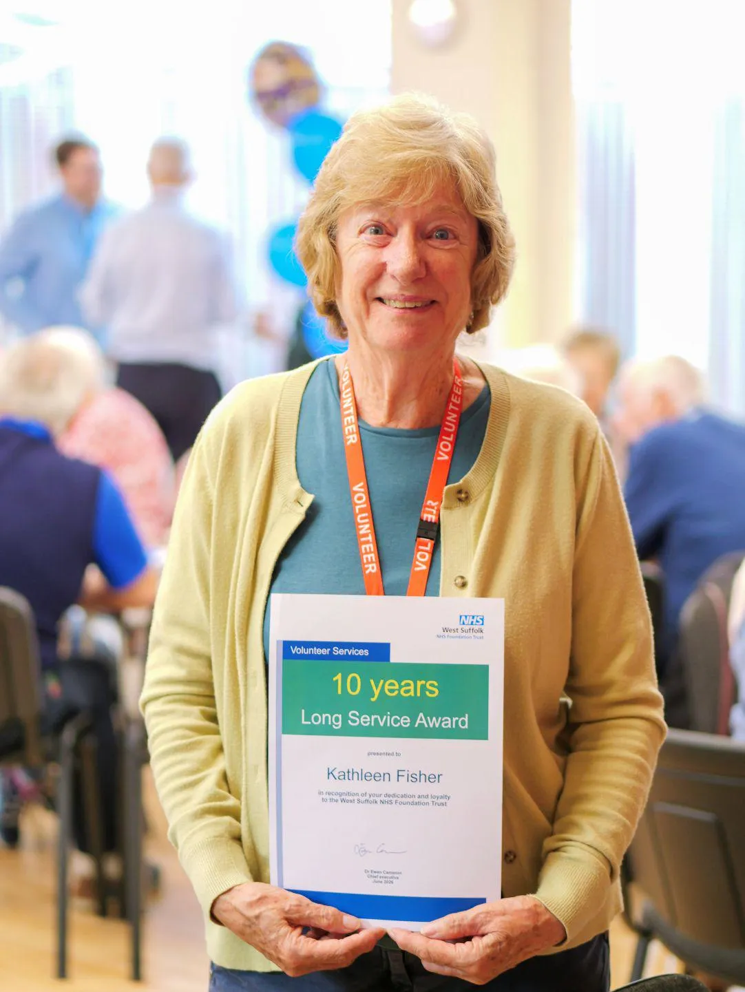 Kathleen fisher, smiling and holding her 10 years long service award