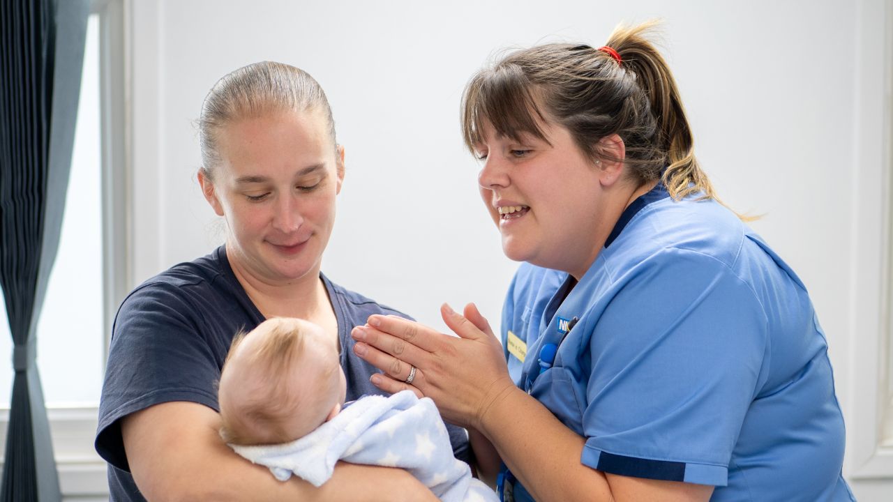 Paediatric nurse with an infant patient and their mother