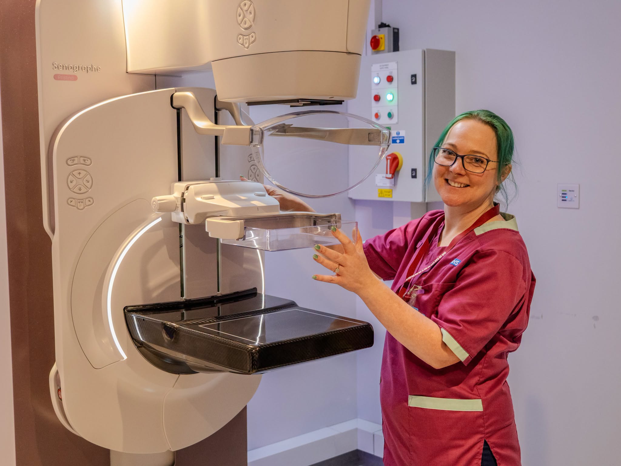 Radiographer standing  and smiling with breast screening equipment