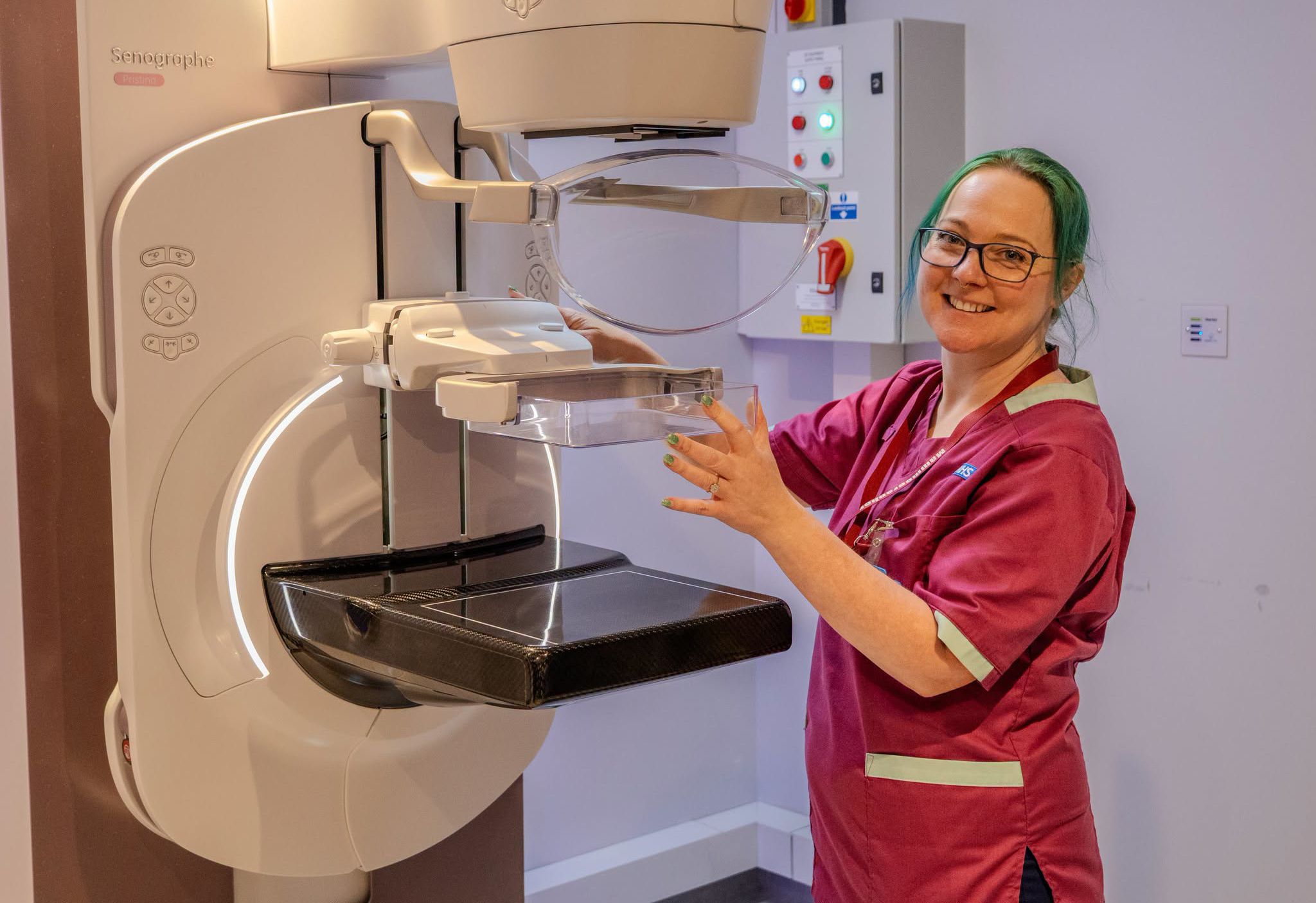 Radiographer standing and smiling with breast screening equipment