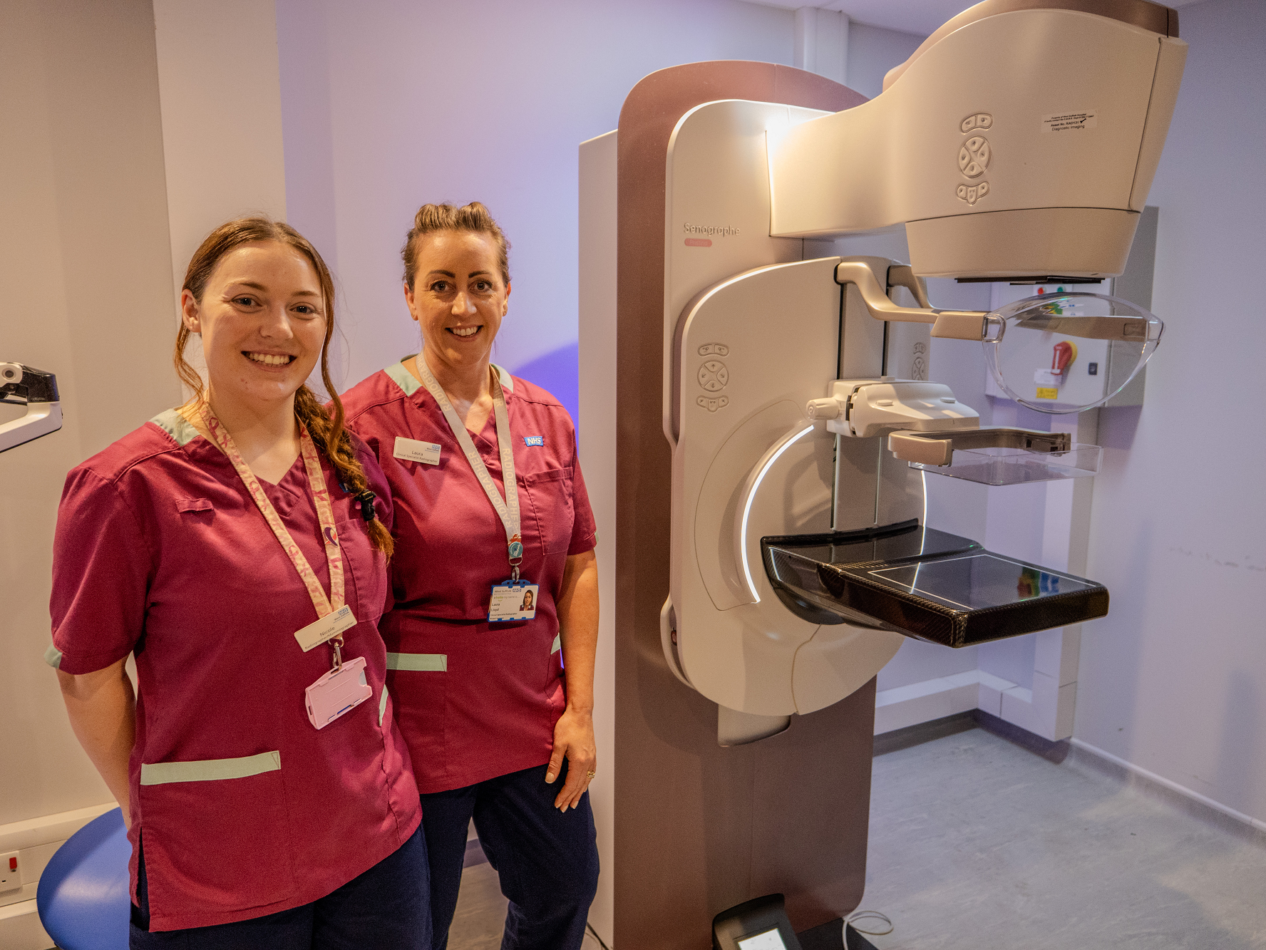 Radiographers standing next to breast screening equipment