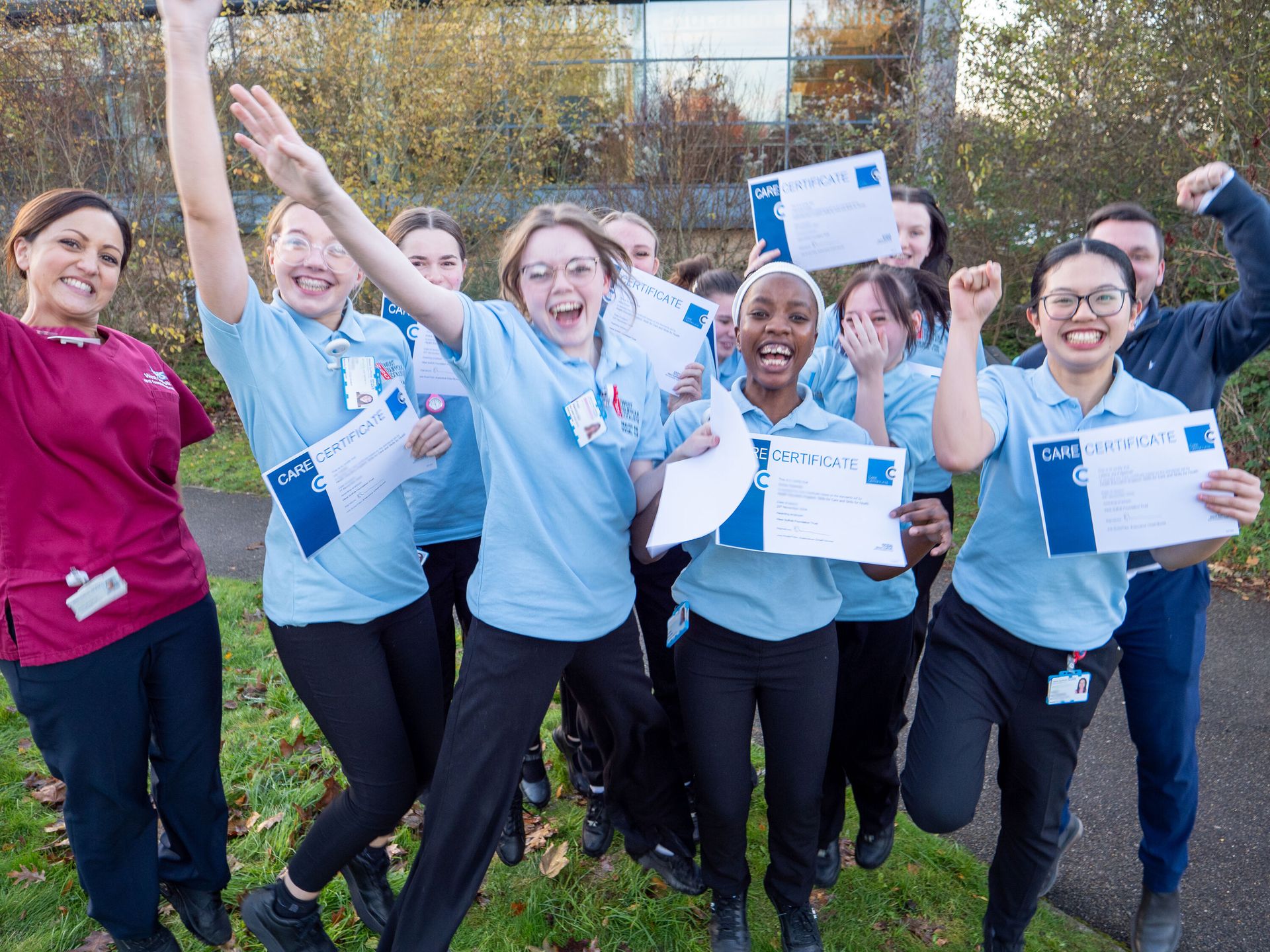 T level students jumping in the air with their care certificate